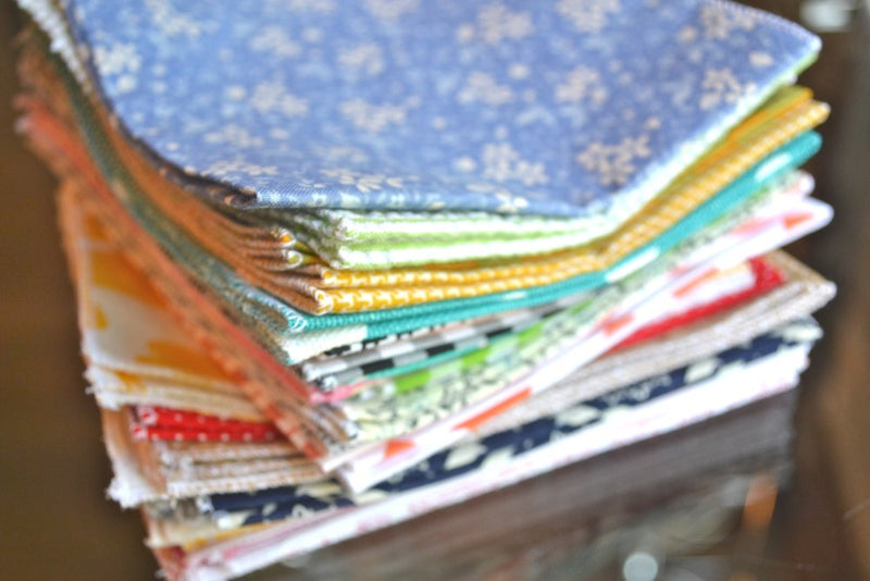 bargain stack of cloth napkins with variety of patterns on wooden table