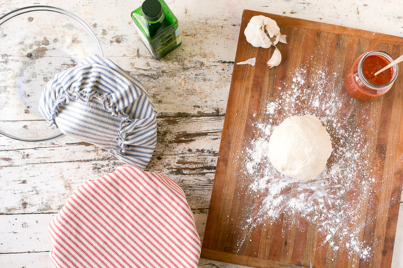 baking table with dough, bowl, and fabric bowl cover